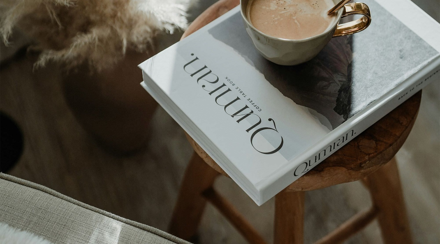 a cup of coffee on a book on a stool in a living room