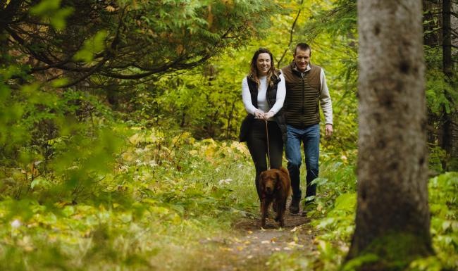 a man and woman walking a dog in the woods